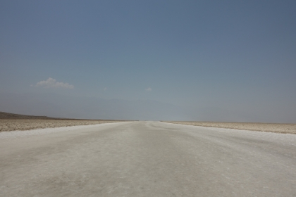 No, it's not a white paved road, it's part of the huge Badwater salt flat. The minerals get deposited here from flood waters that wash down the local mountains. The water forms temporary lakes that evaporate and then leave the minerals behind.